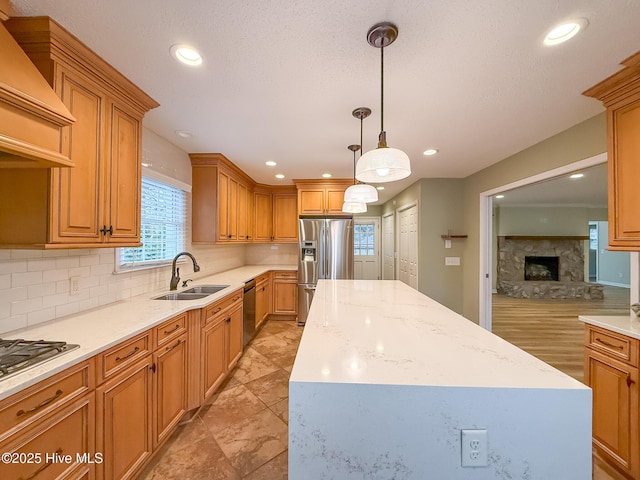 kitchen with a fireplace, a center island, sink, and appliances with stainless steel finishes