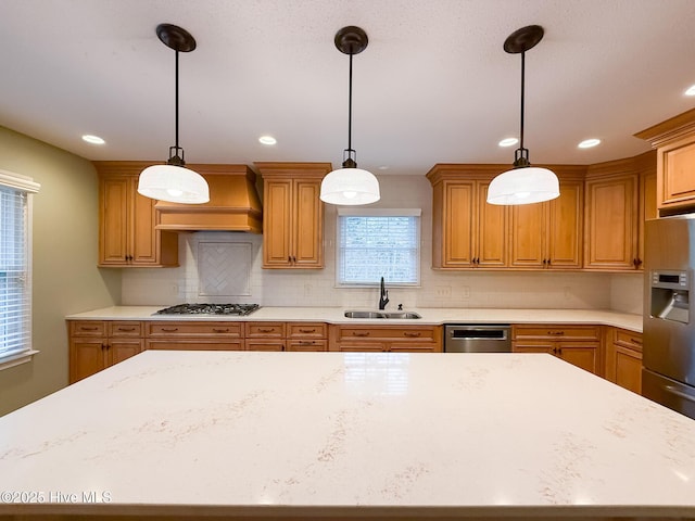 kitchen with decorative backsplash, appliances with stainless steel finishes, custom exhaust hood, sink, and hanging light fixtures