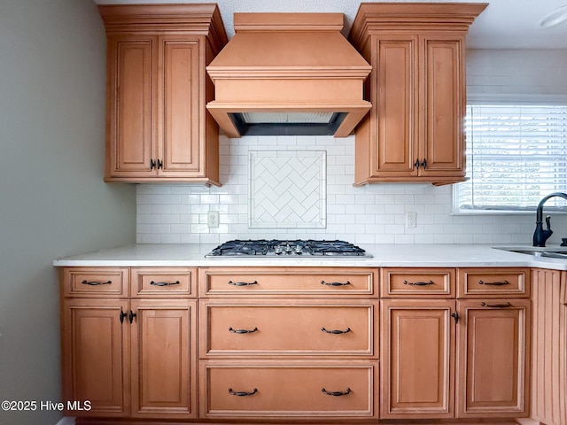 kitchen with sink, tasteful backsplash, stainless steel gas stovetop, and custom exhaust hood