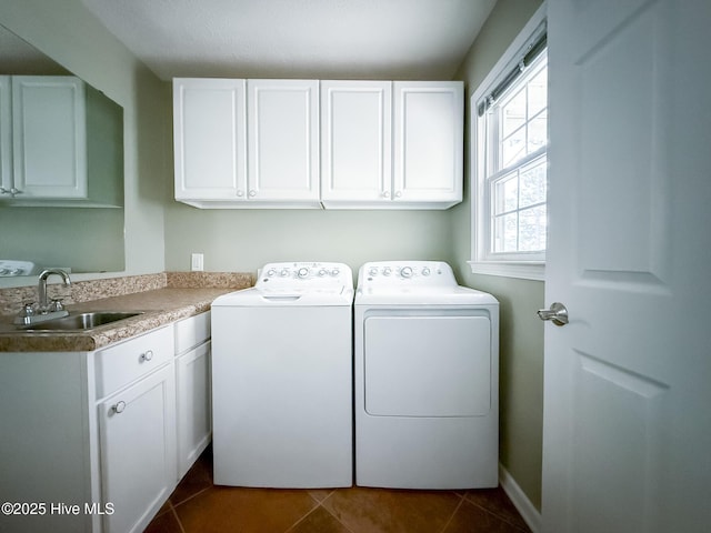 washroom with cabinets, dark tile patterned floors, sink, and washing machine and dryer