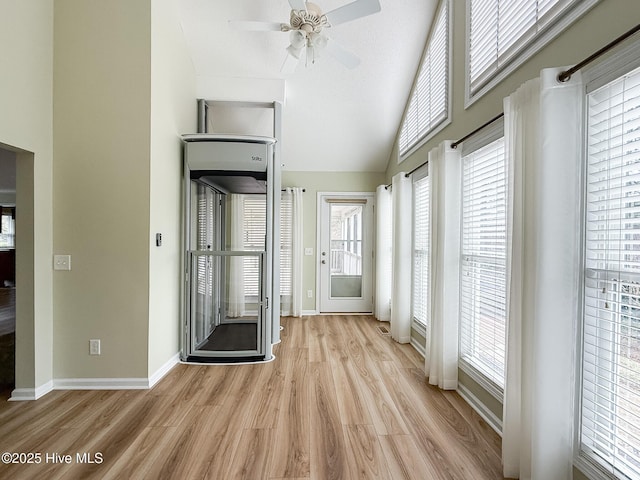 interior space with ceiling fan, high vaulted ceiling, and light wood-type flooring