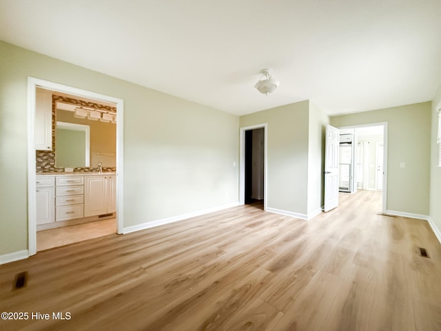 unfurnished bedroom with light hardwood / wood-style floors, sink, connected bathroom, and a closet