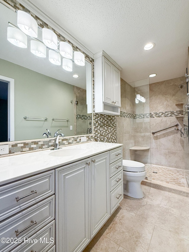 bathroom featuring vanity, toilet, a textured ceiling, tasteful backsplash, and a tile shower