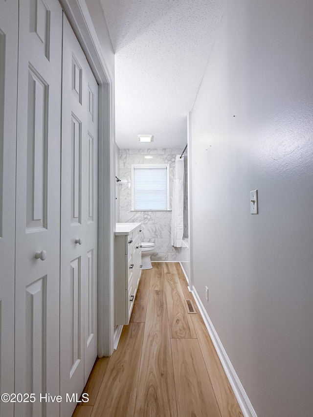 hall featuring light hardwood / wood-style floors and a textured ceiling