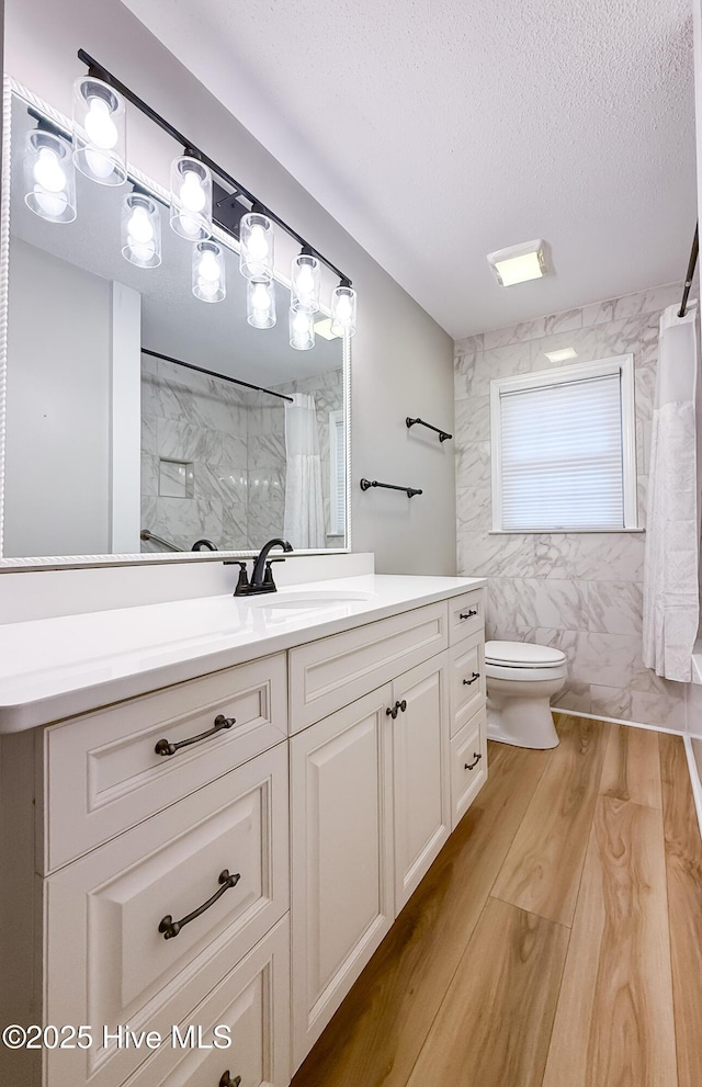 bathroom with a shower with curtain, hardwood / wood-style floors, a textured ceiling, toilet, and vanity