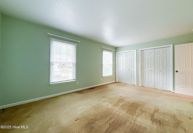 unfurnished bedroom featuring multiple closets and carpet