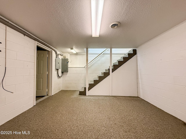 basement featuring a textured ceiling and electric panel