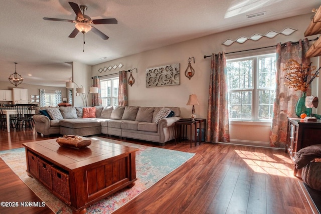 living room with a textured ceiling, light wood-type flooring, and ceiling fan