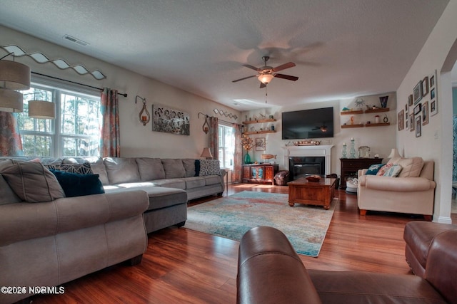 living room featuring ceiling fan, wood-type flooring, and a textured ceiling