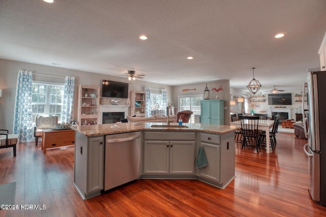 kitchen with appliances with stainless steel finishes, ceiling fan, sink, dark hardwood / wood-style floors, and a kitchen island