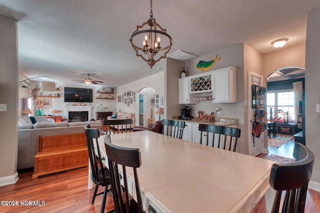 dining space featuring ceiling fan with notable chandelier, light hardwood / wood-style floors, and a textured ceiling