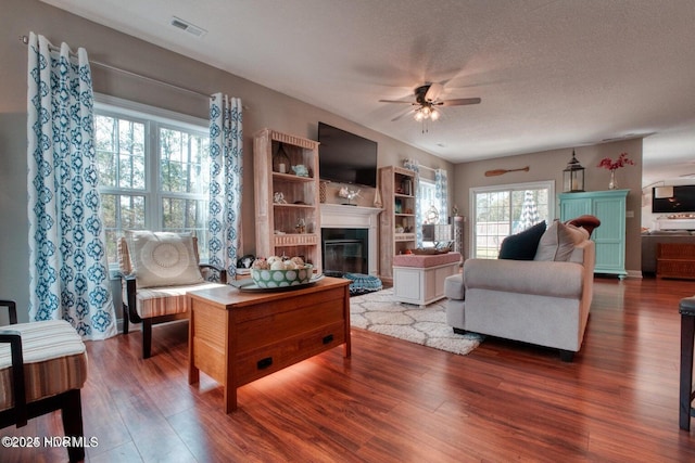 living room featuring ceiling fan, wood-type flooring, and a textured ceiling