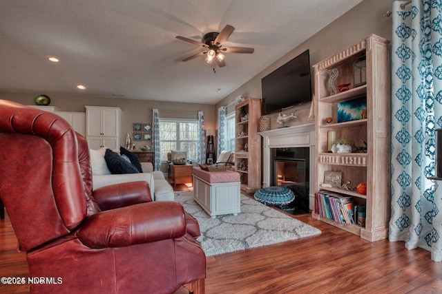 living room featuring ceiling fan, light hardwood / wood-style flooring, and a textured ceiling