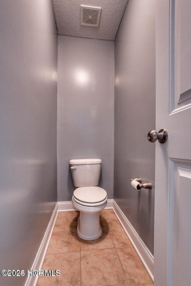 bathroom with tile patterned floors, toilet, and a textured ceiling