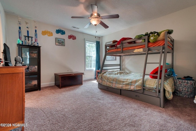 carpeted bedroom featuring ceiling fan and a textured ceiling