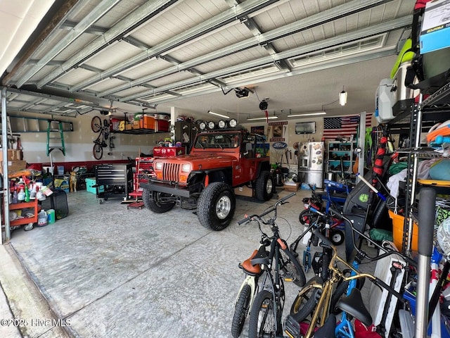 garage with stainless steel refrigerator with ice dispenser, a workshop area, and a garage door opener