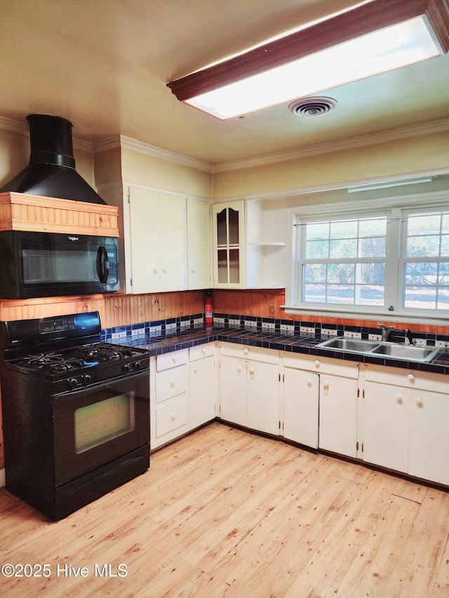 kitchen with white cabinets, sink, tile countertops, and black appliances