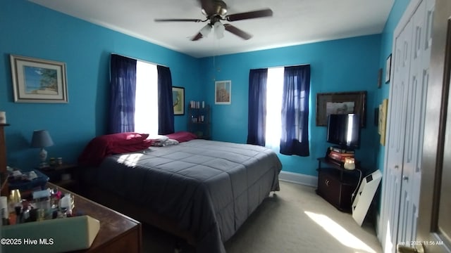 bedroom featuring multiple windows, a closet, ceiling fan, and light colored carpet