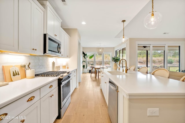 kitchen with appliances with stainless steel finishes, pendant lighting, a center island with sink, and sink