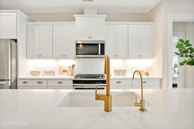 kitchen with white cabinets, tasteful backsplash, and appliances with stainless steel finishes