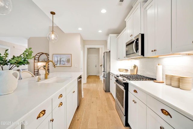 kitchen featuring sink, white cabinetry, tasteful backsplash, hanging light fixtures, and appliances with stainless steel finishes