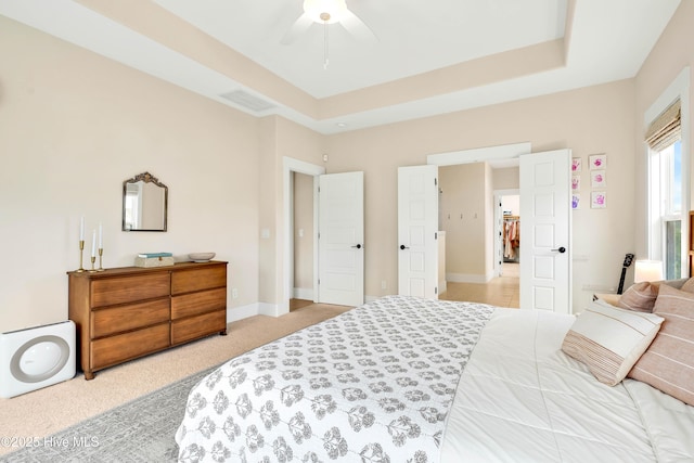 bedroom with a raised ceiling, light carpet, and ceiling fan