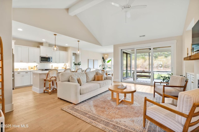 living room featuring ceiling fan, light wood-type flooring, high vaulted ceiling, and beamed ceiling