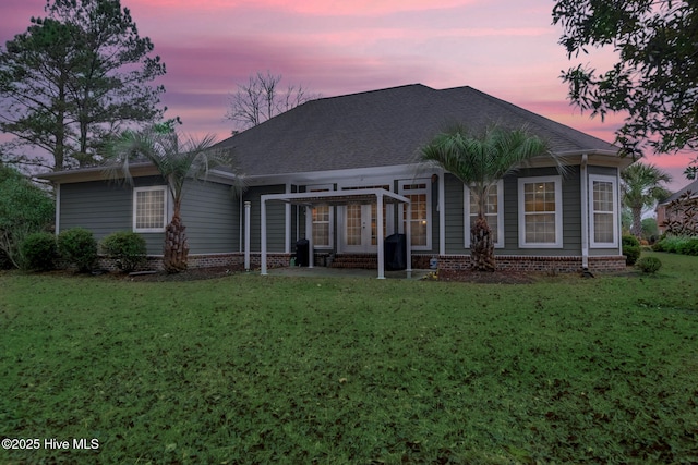 back house at dusk featuring a yard and french doors