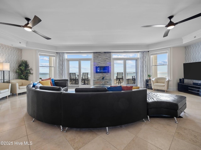 tiled living room with a raised ceiling, ceiling fan, and ornamental molding