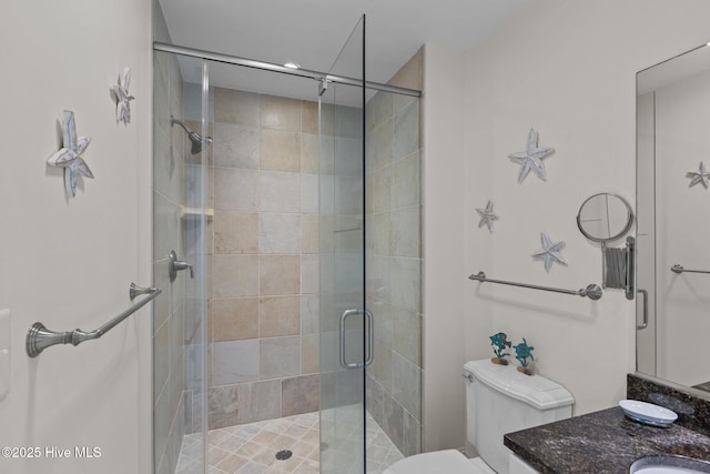 bathroom with toilet, vanity, and a stall shower