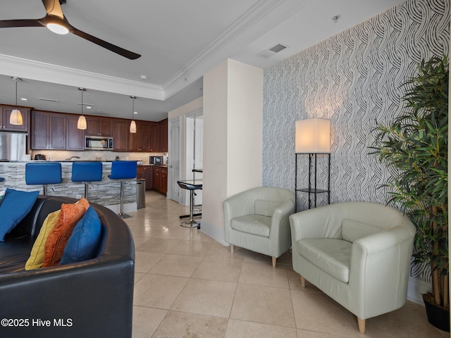 living room with a tray ceiling, crown molding, light tile patterned floors, and ceiling fan