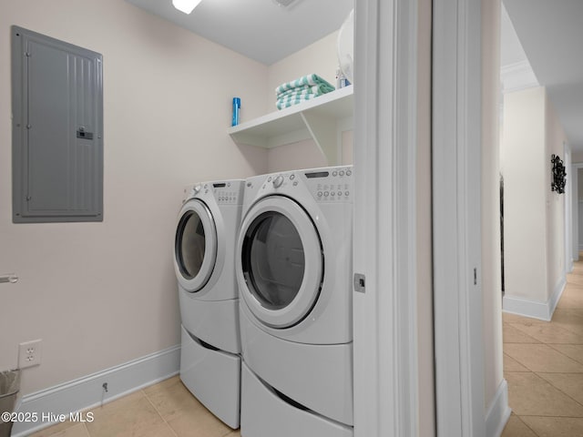 laundry area featuring light tile patterned floors, electric panel, and washing machine and clothes dryer