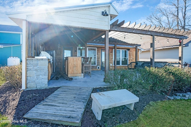 back of property featuring a pergola and exterior kitchen