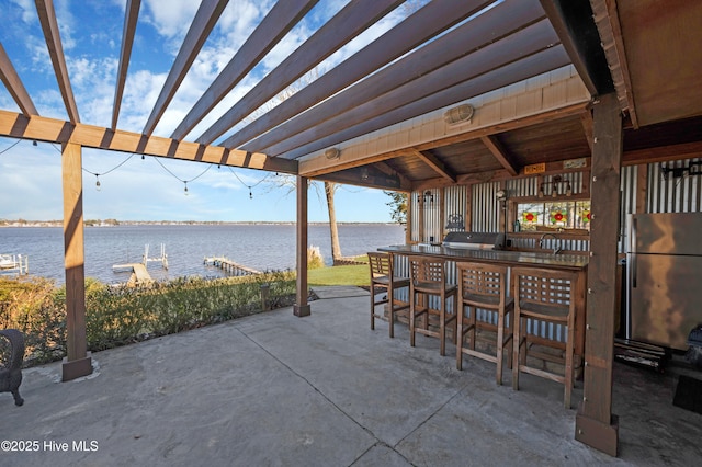 view of patio with area for grilling, a pergola, a water view, and an outdoor bar