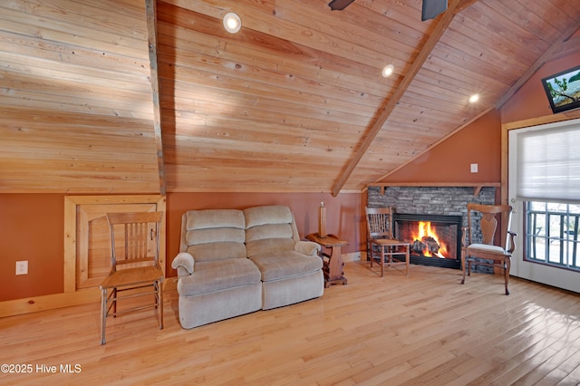 living room with a stone fireplace, vaulted ceiling with beams, ceiling fan, light wood-type flooring, and wood ceiling