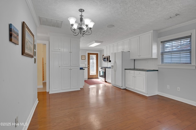 kitchen featuring appliances with stainless steel finishes, white cabinetry, plenty of natural light, and ornamental molding