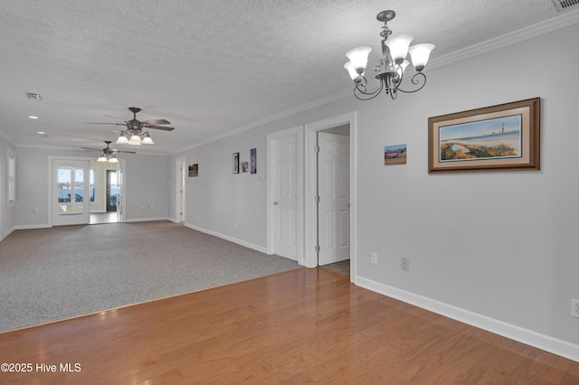 carpeted spare room featuring ceiling fan with notable chandelier, ornamental molding, and a textured ceiling