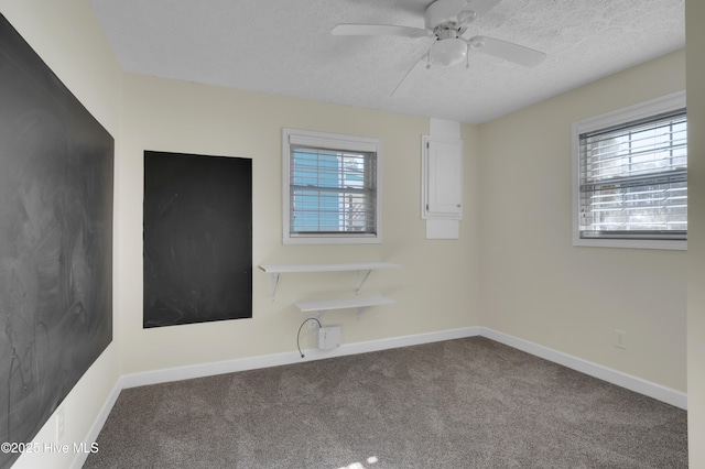 spare room featuring a wealth of natural light, ceiling fan, carpet, and a textured ceiling