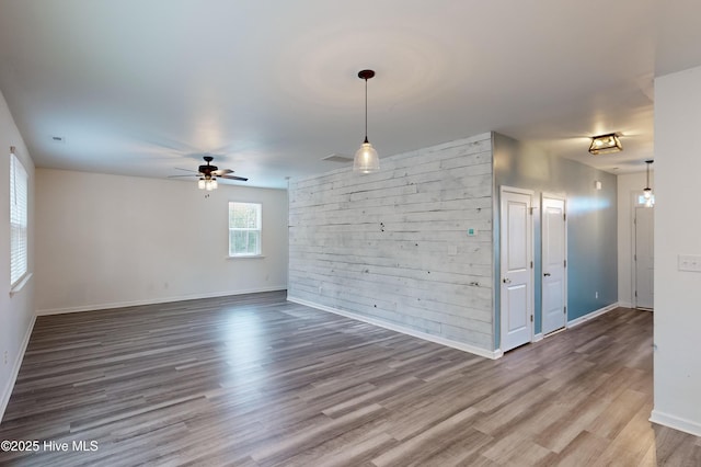 spare room with hardwood / wood-style flooring, ceiling fan, and wooden walls