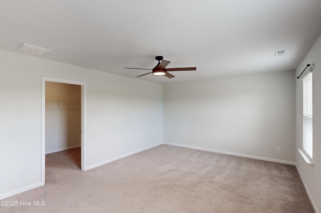 empty room with light carpet, a barn door, and ceiling fan