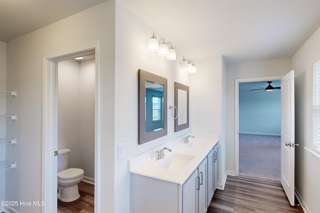 bathroom with ceiling fan, vanity, wood-type flooring, and toilet