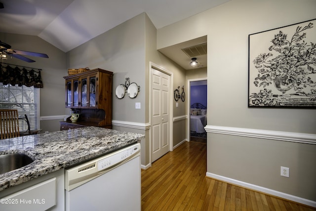 kitchen with ceiling fan, white dishwasher, stone countertops, vaulted ceiling, and light wood-type flooring