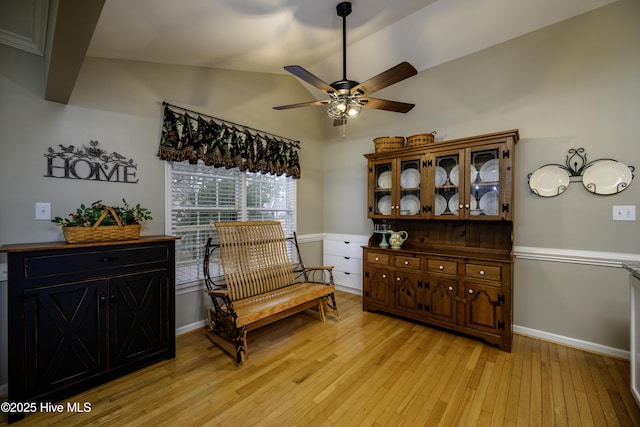 living area featuring ceiling fan, light wood-type flooring, and vaulted ceiling