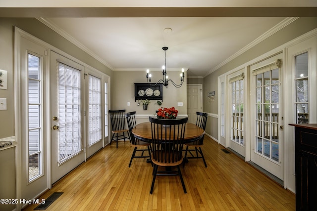 dining space with ornamental molding, light hardwood / wood-style flooring, and a notable chandelier