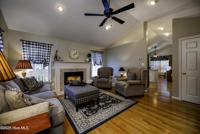 living room featuring hardwood / wood-style floors, ceiling fan, a tile fireplace, and vaulted ceiling