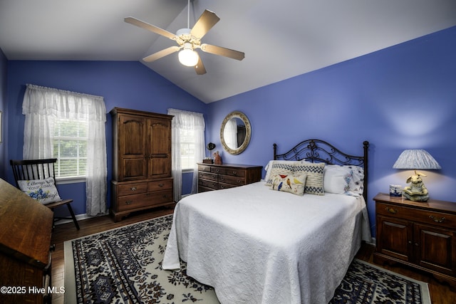 bedroom featuring ceiling fan, dark hardwood / wood-style flooring, multiple windows, and vaulted ceiling