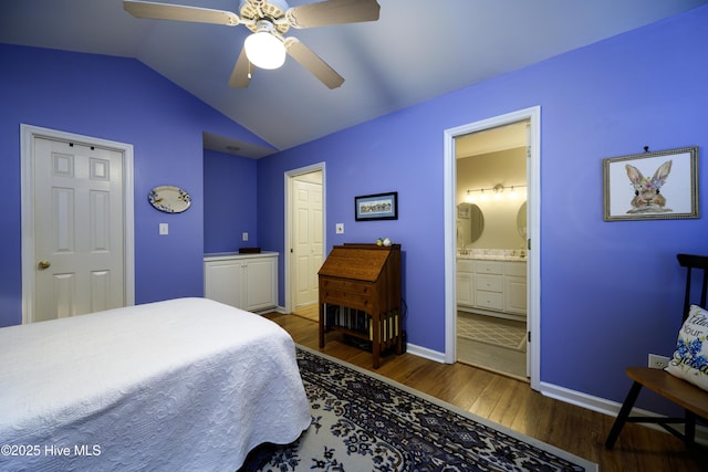 bedroom featuring dark hardwood / wood-style flooring, ensuite bath, ceiling fan, and lofted ceiling