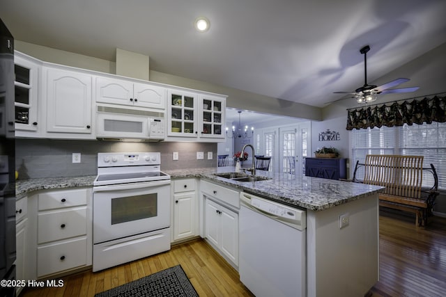 kitchen with kitchen peninsula, white appliances, sink, pendant lighting, and white cabinets