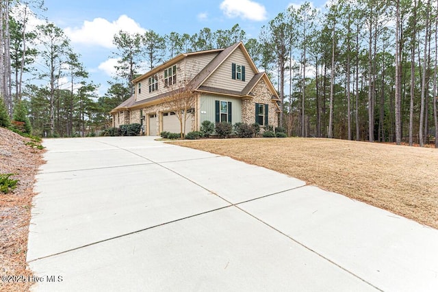 view of front of property with stone siding, driveway, a front yard, and a garage