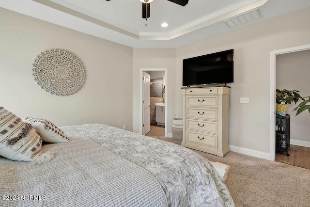 bedroom with a raised ceiling, crown molding, ceiling fan, connected bathroom, and light colored carpet